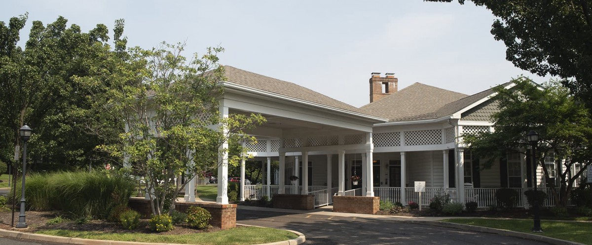 A building entrance with a covered canopy and surrounding greenery.