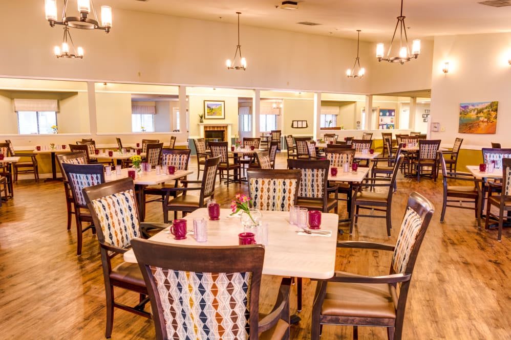 A spacious dining area with neatly arranged tables and chairs under warm lighting.