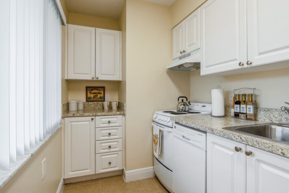 A compact kitchen with white cabinets and modern appliances.