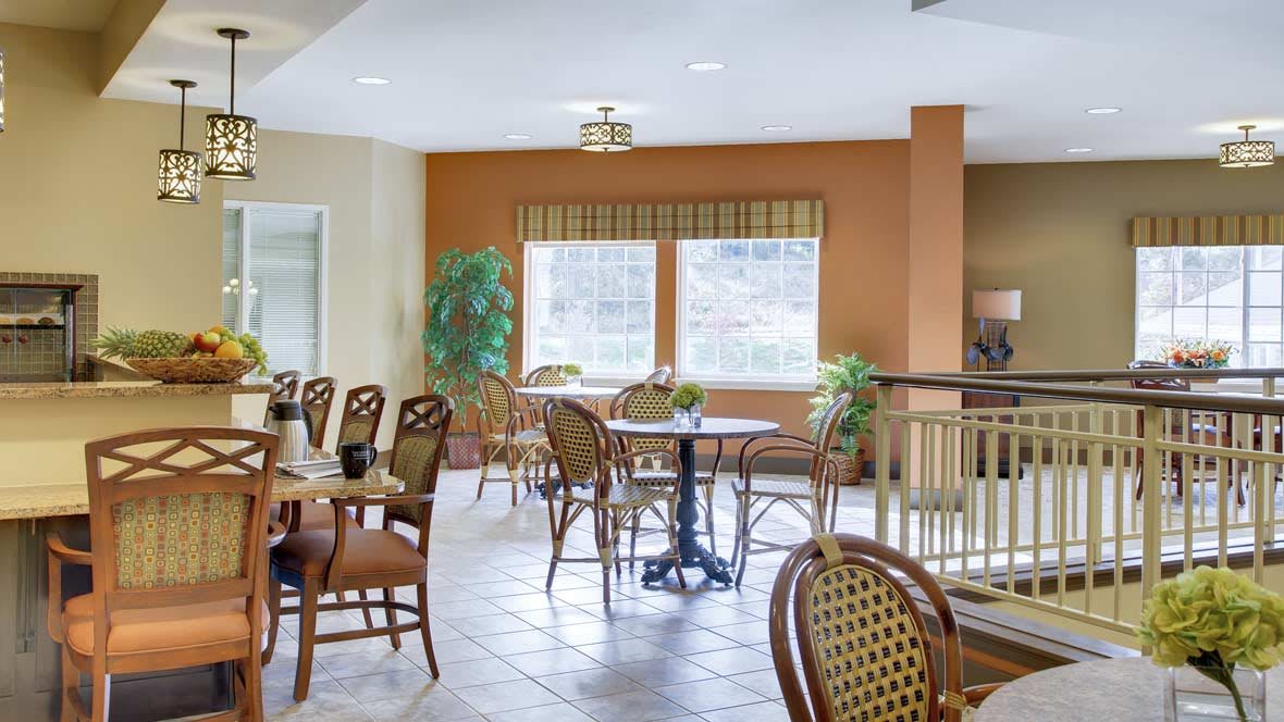 A cozy dining area with tables, chairs, and large windows providing natural light.