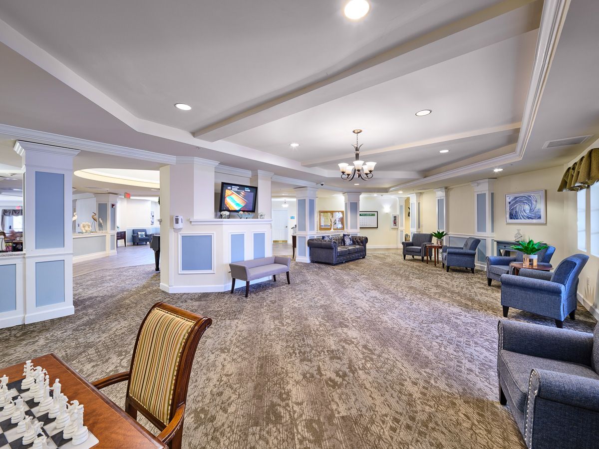 A spacious and elegantly designed lobby area featuring comfortable seating, a chandelier, and a television.