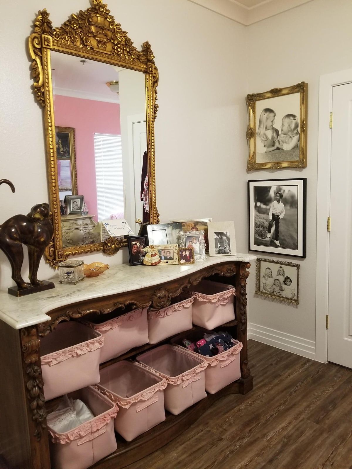 A beautifully decorated hallway with a large mirror above a vintage console table, featuring storage baskets and various decorative items.