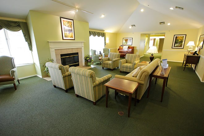 A cozy living room with multiple couches and chairs arranged around a central fireplace.