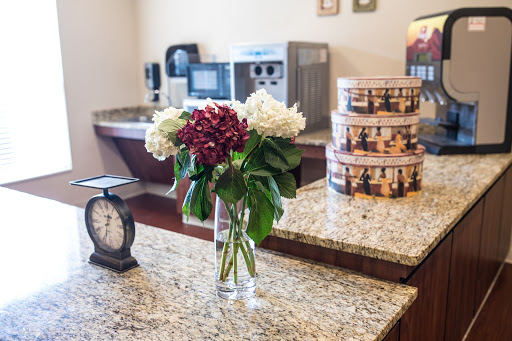 A cozy kitchen setup featuring a vibrant bouquet of flowers on a granite countertop, complemented by a vintage clock and food storage canisters.