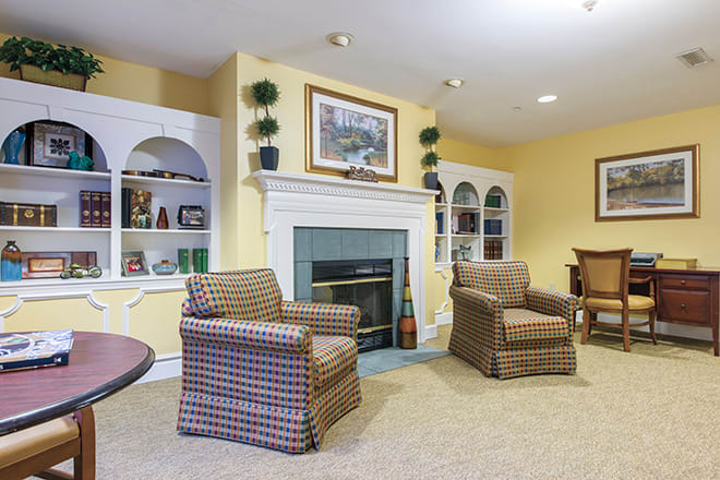 A cozy living room featuring a fireplace flanked by built-in bookshelves and two patterned armchairs.