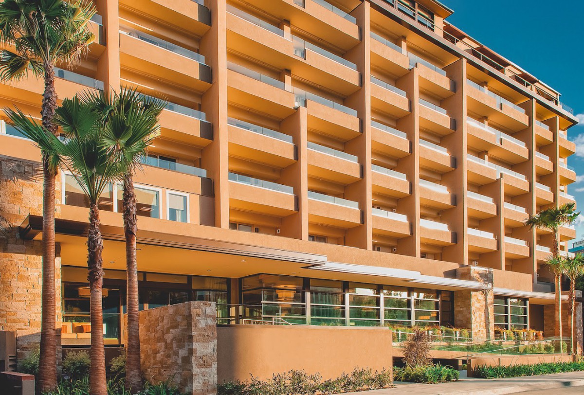 A modern hotel building with multiple balconies under a clear blue sky.