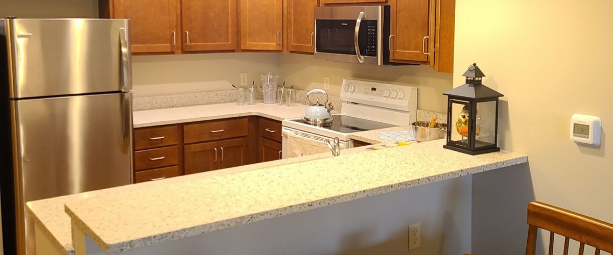 A modern kitchen with wooden cabinets and a range of appliances.