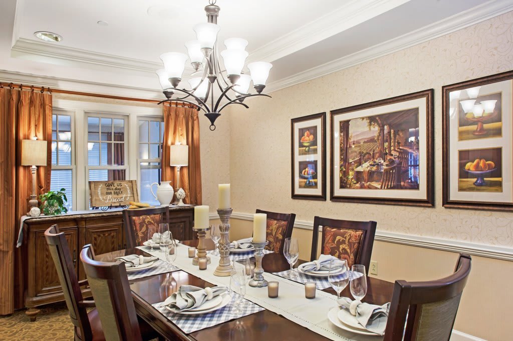 A beautifully decorated dining room with an elegant chandelier and a set dining table.