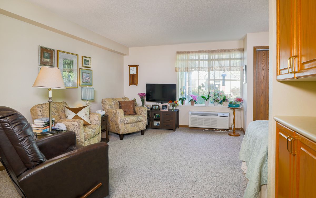 A cozy living room with comfortable seating, a television, and a large window letting in natural light.