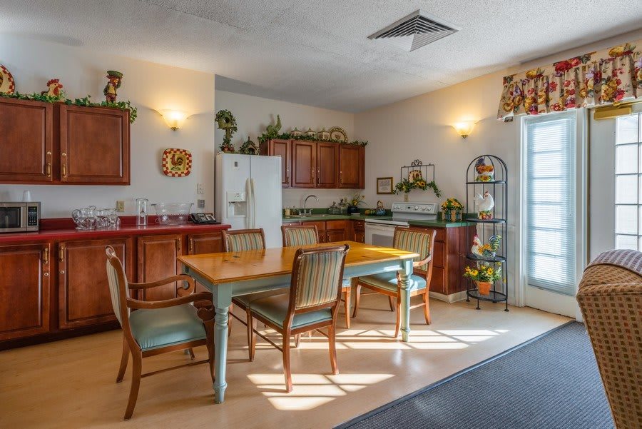A cozy kitchen and dining area featuring wooden cabinets, a dining table with chairs, and decorative elements.