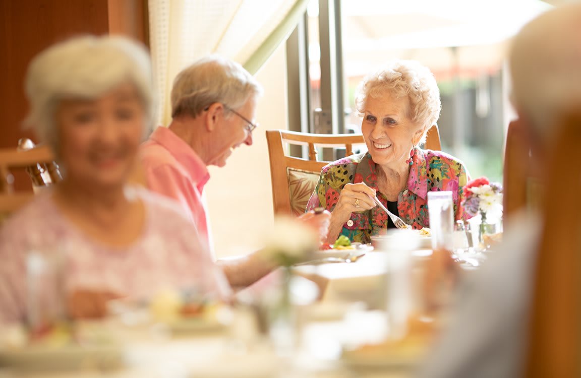 A group of elderly people enjoying a meal and conversation in a restaurant setting.