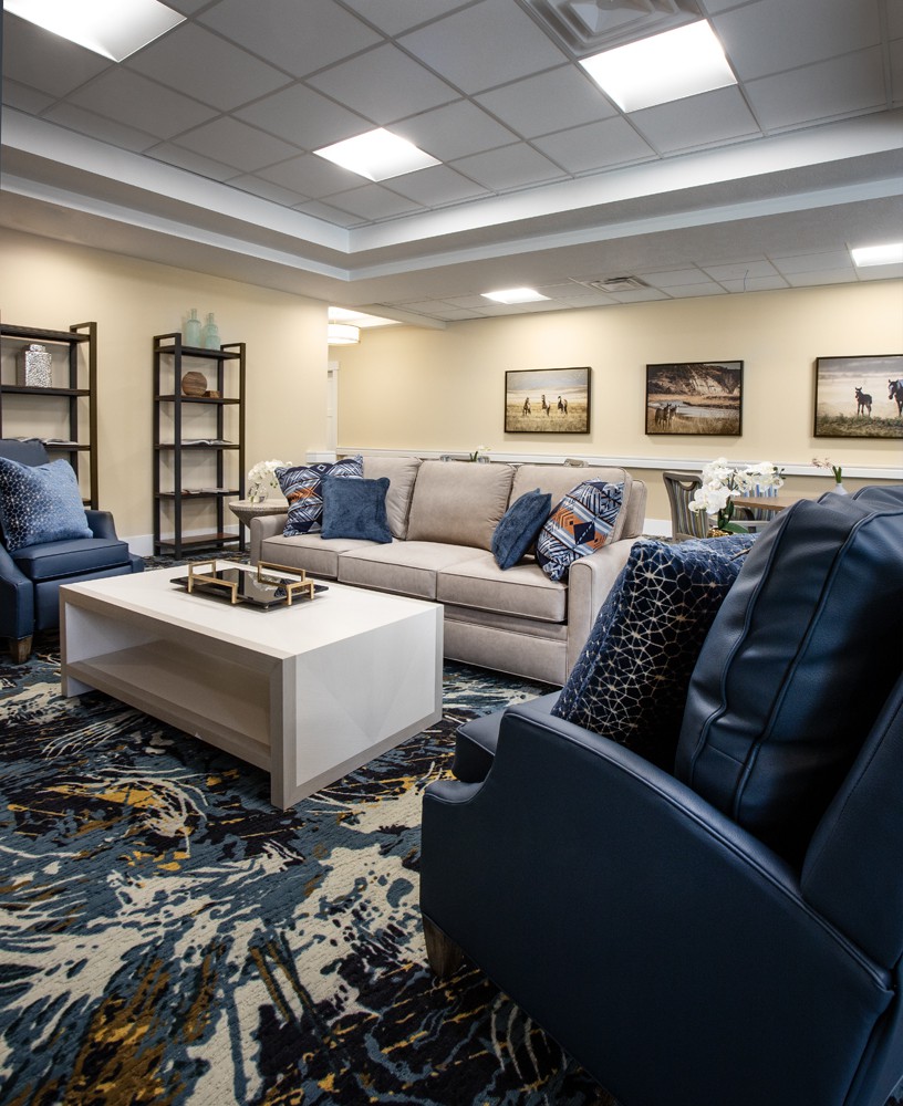 A modern living room with comfortable sofas and armchairs, featuring a stylish rug and decorative elements.