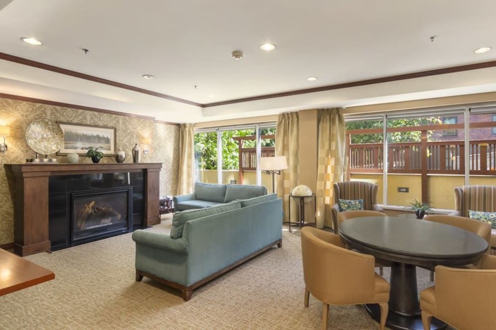 A spacious living room with elegant furniture, featuring a fireplace and large windows.