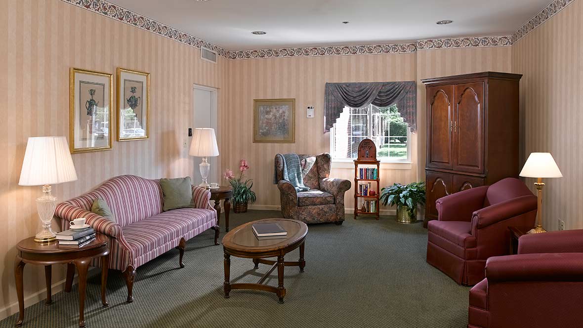 A cozy vintage-style living room with striped wallpaper and classic furniture.