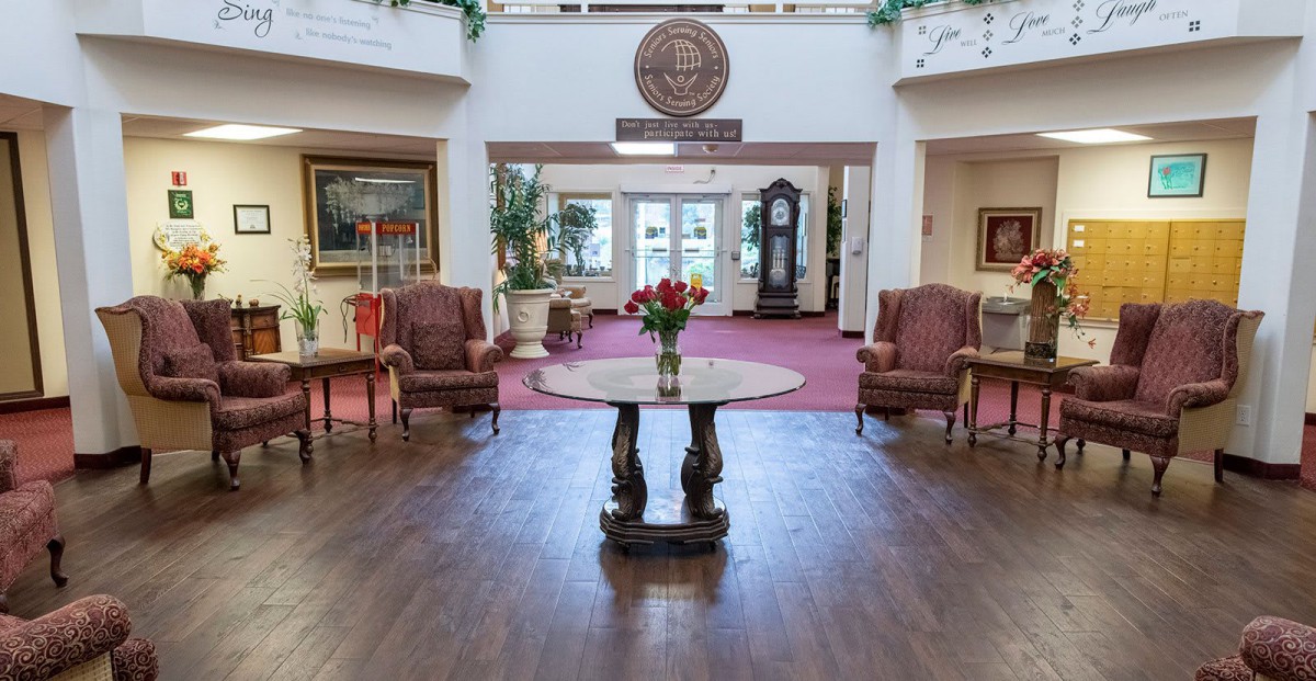 A welcoming lobby interior featuring a central table with flowers and comfortable seating.