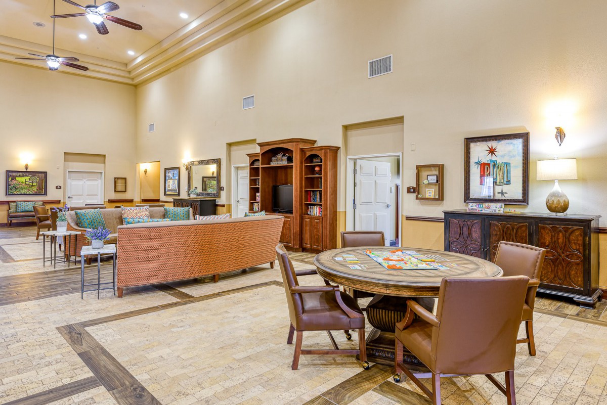 A spacious and well-decorated living room with a cozy seating area, round table, and artwork on the walls.