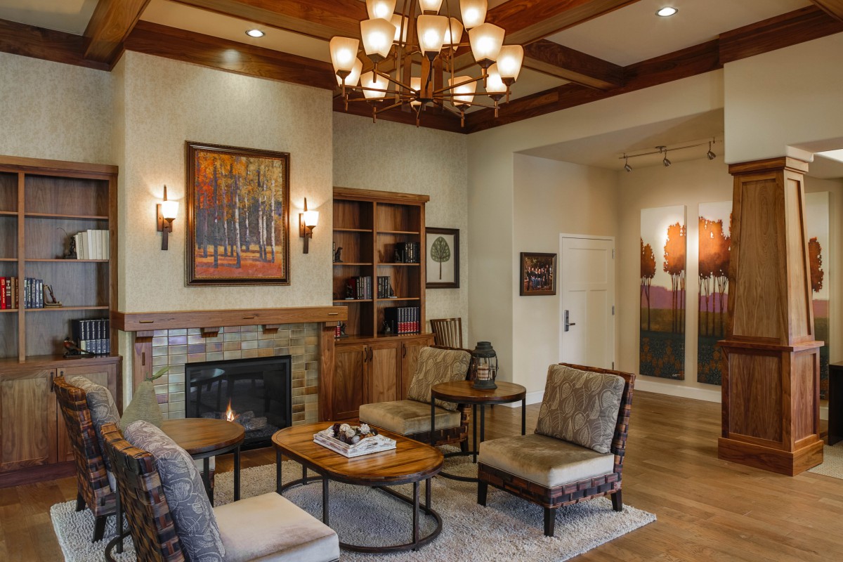 A cozy living room with elegant furnishings, a warm fireplace, and a grand chandelier.