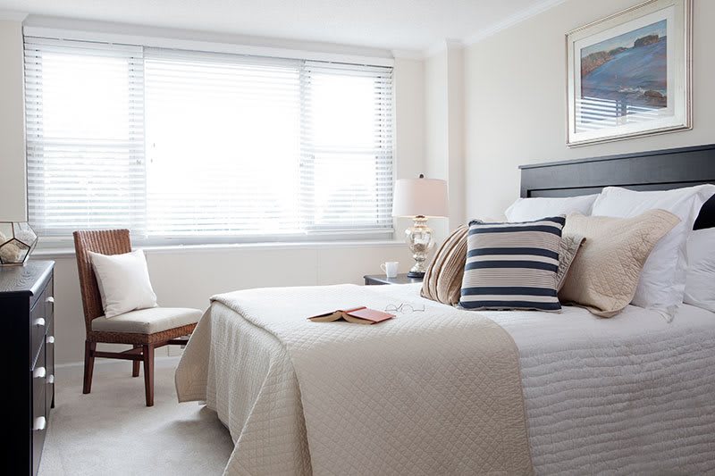A modern minimalist bedroom filled with natural light, featuring a neatly made bed and stylish decor.