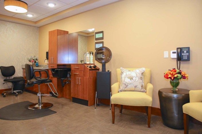 A cozy salon interior with a barber chair, vanity, and waiting area.