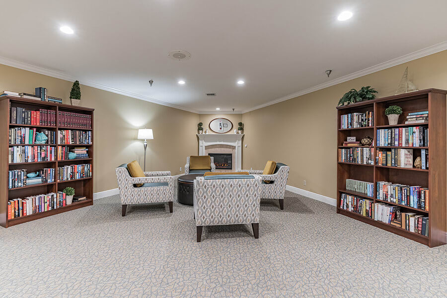 A cozy living room with a seating area surrounded by bookshelves and elegant decor.