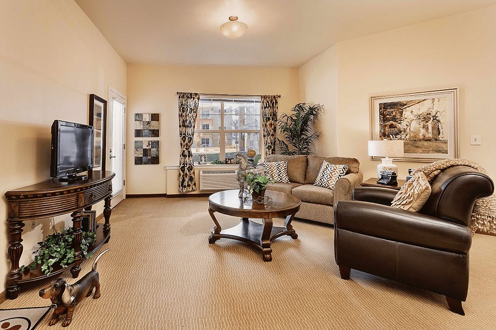 A cozy living room featuring a comfortable sofa set and a central coffee table, beautifully decorated with curtains and artwork.