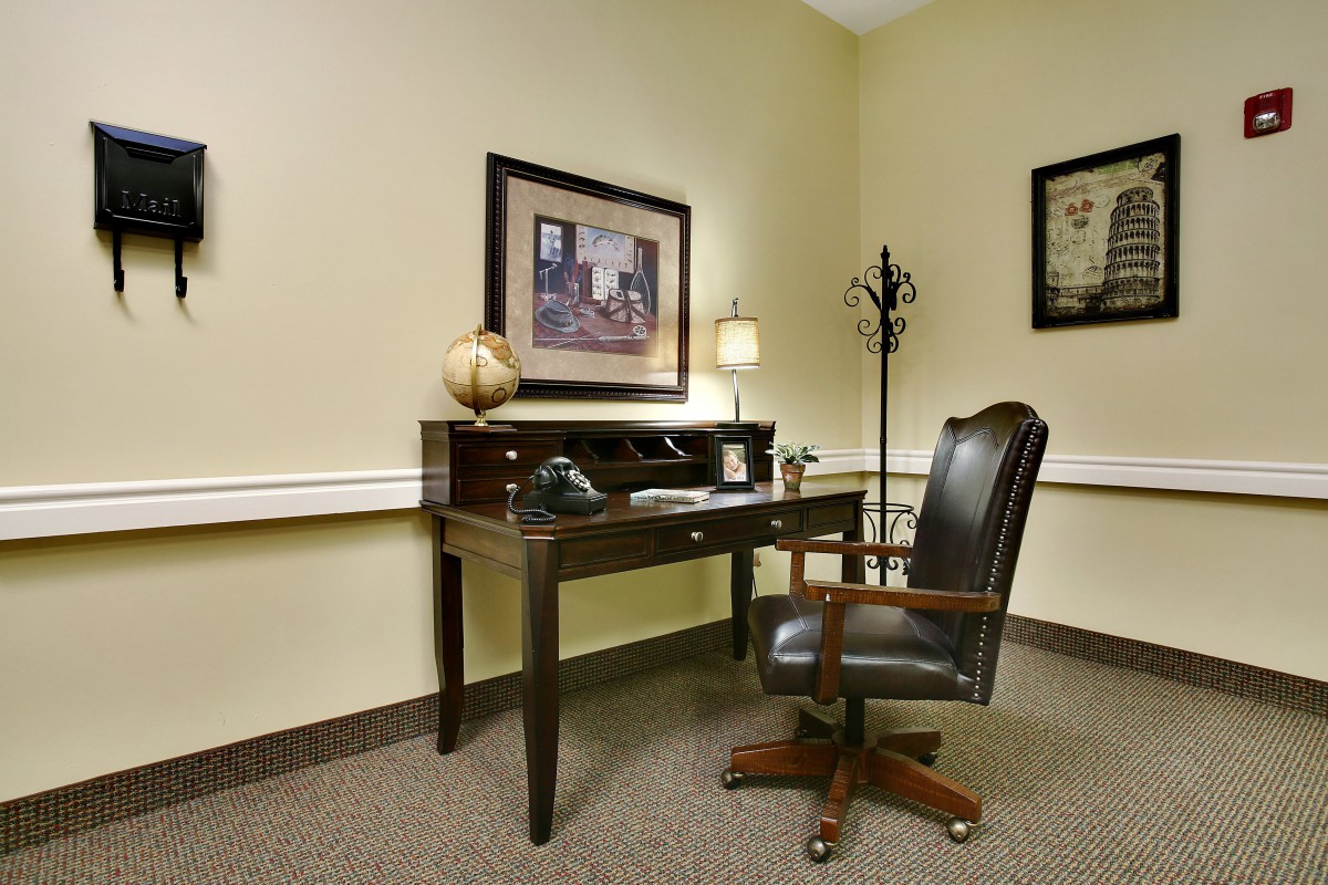A well-organized office corner with a desk and chair, complemented by wall art and a lamp.