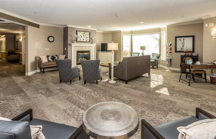 A spacious and well-lit living room with modern decor, featuring a fireplace and comfortable seating.