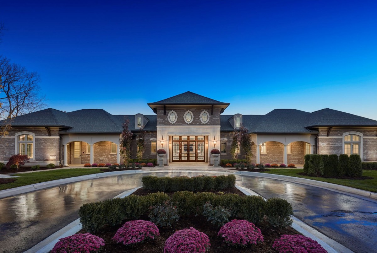 A luxurious mansion with elegant landscaping illuminated during the evening.