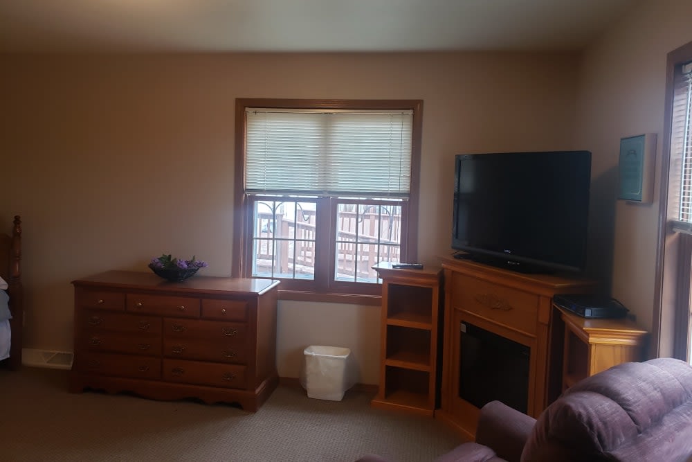 A cozy living room with a television, wooden furniture, and a window.
