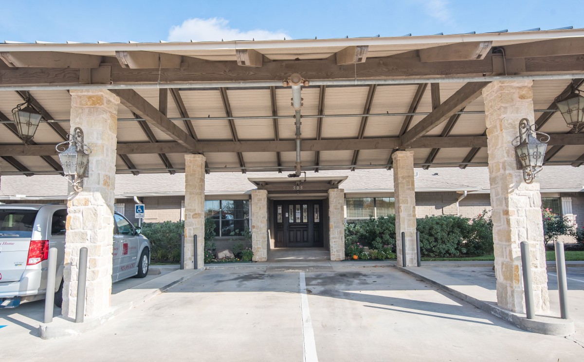 Covered entrance of a building with stone columns and wooden awning.
