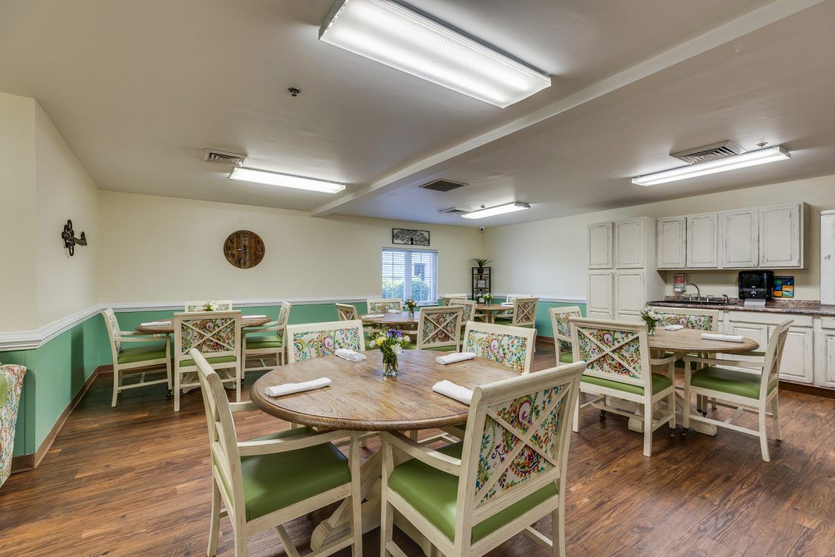 A spacious and well-lit dining area with neatly arranged tables and chairs, featuring a warm wooden floor.