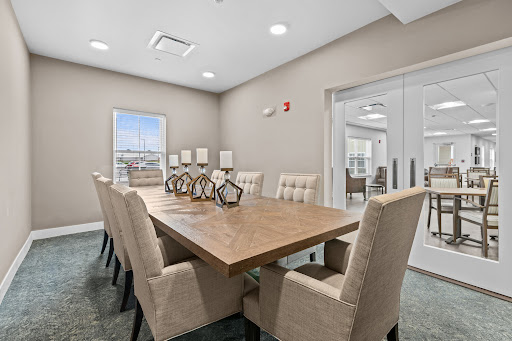 A modern meeting room featuring a spacious wooden conference table surrounded by comfortable upholstered chairs, designed for professional gatherings.