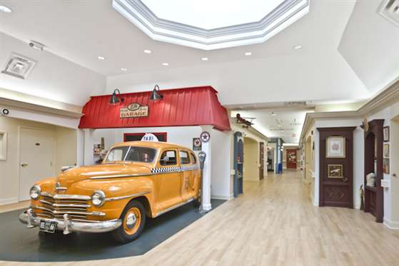 An indoor exhibit features a vintage car parked in front of a retro-style gas station setup.