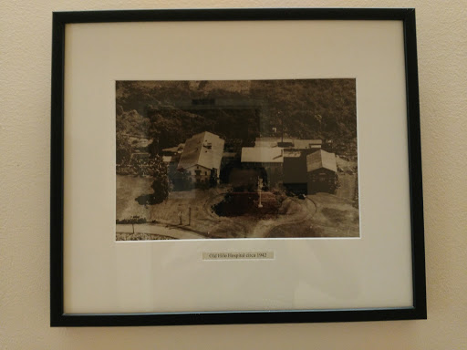 A serene black and white photograph depicting rural buildings surrounded by nature.
