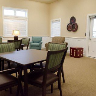 A cozy living room with a table and chairs, adorned with wall decor and a lamp on a side table.