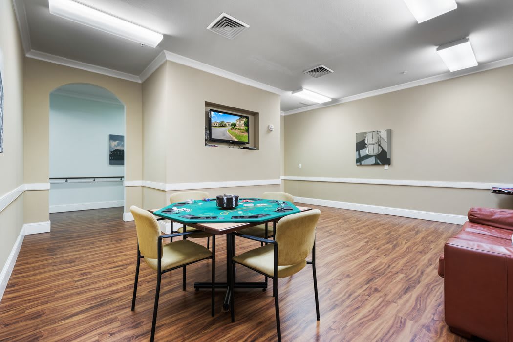 A spacious game room with a poker table and chairs on a hardwood floor, adorned with artwork on the walls.