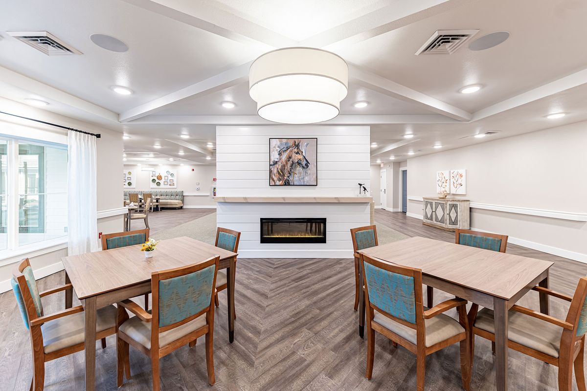 A modern dining area featuring multiple tables and chairs, a central fireplace, and contemporary lighting.