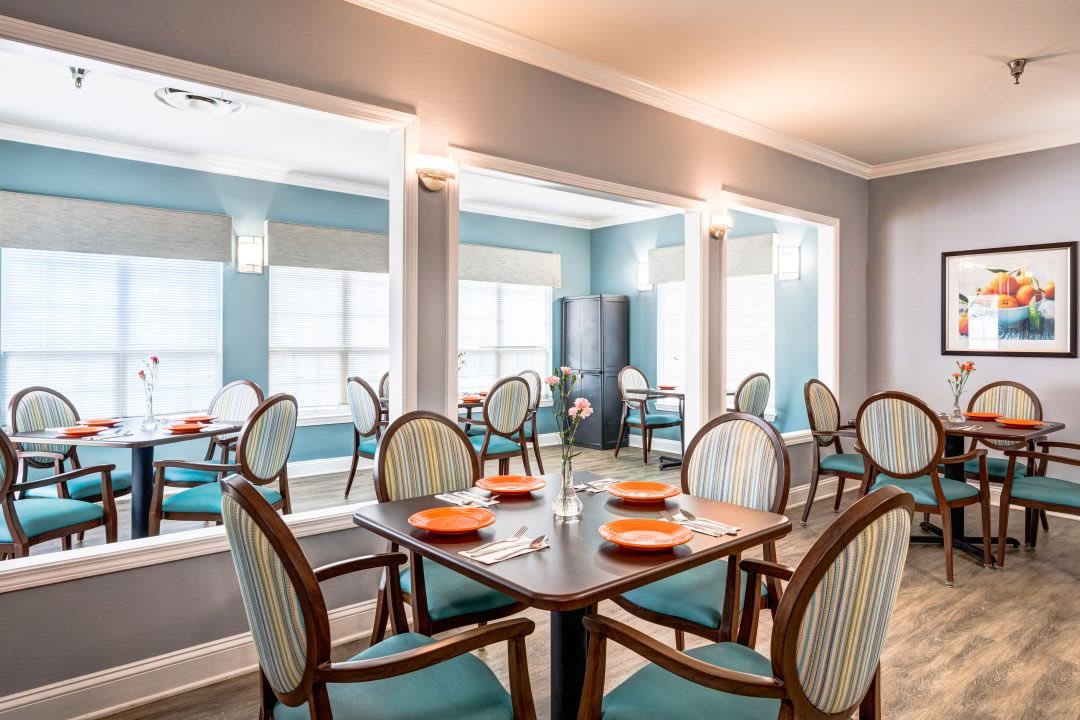A modern dining room with neatly arranged tables and chairs, featuring bright lighting and stylish decor.