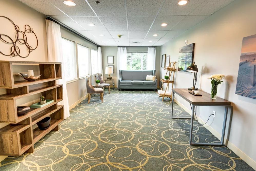 A modern office waiting area with seating, desks, and large windows.