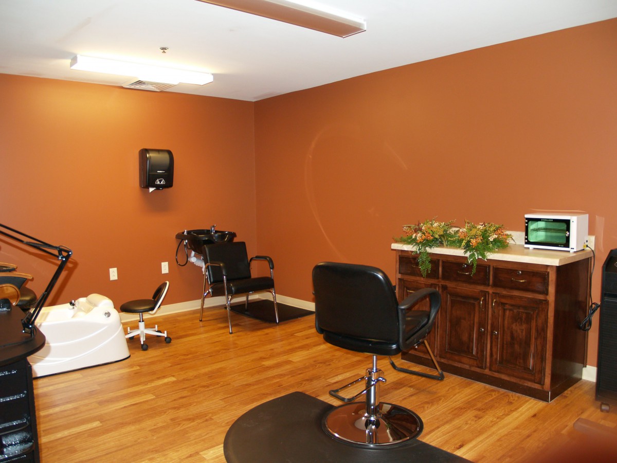 An interior view of a hair salon featuring chairs, a sink, and a wooden floor.
