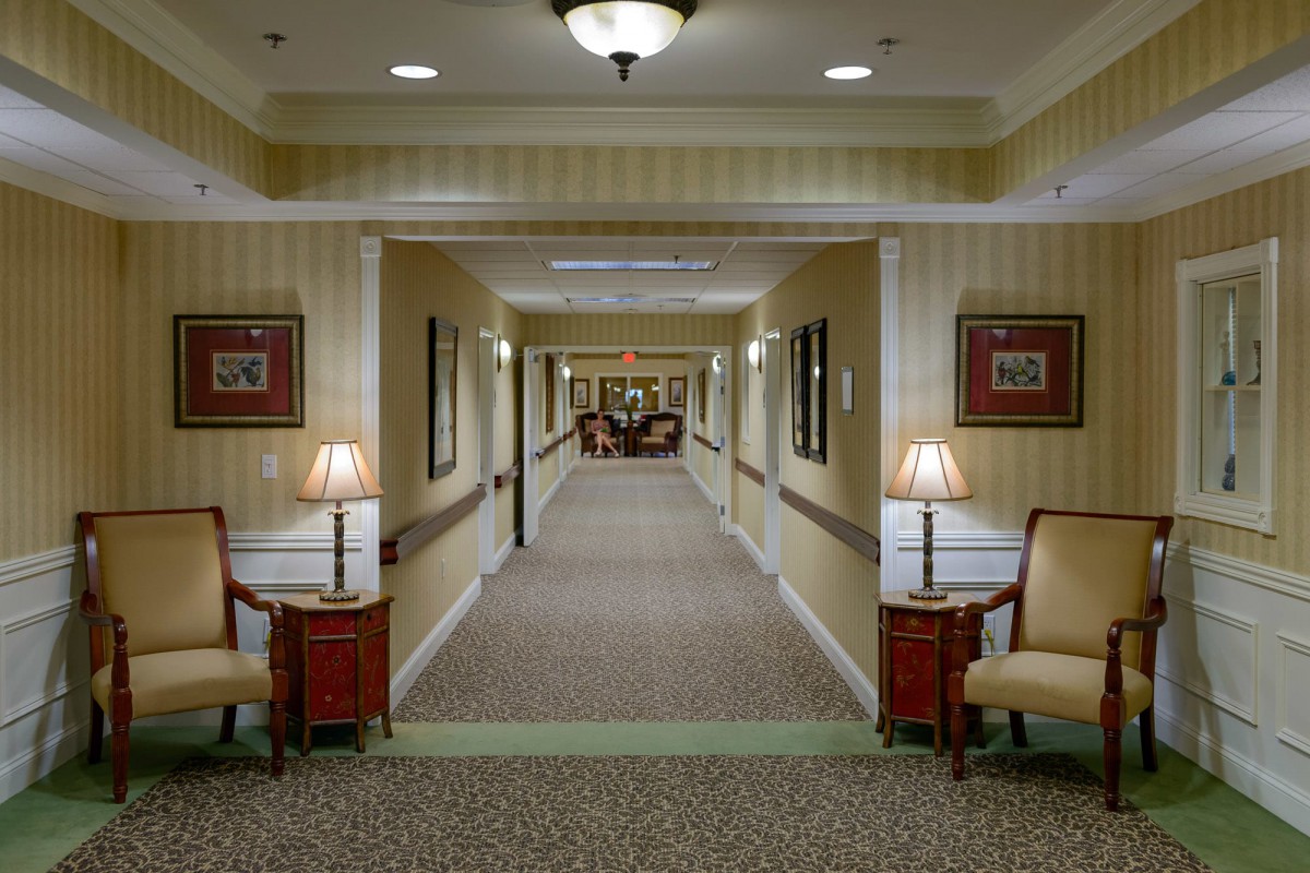 A well-lit hallway with chairs and lamps along the walls.