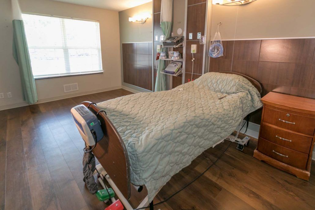 An empty hospital room with a patient bed and medical equipment.