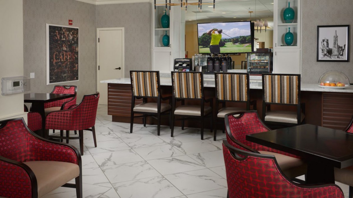 A stylish bar with seating and a marble floor, featuring a television in the background.