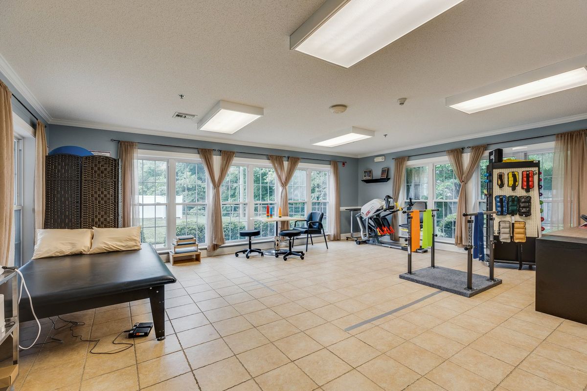 A spacious rehabilitation room equipped with therapy and exercise equipment, featuring large windows that allow ample natural light.