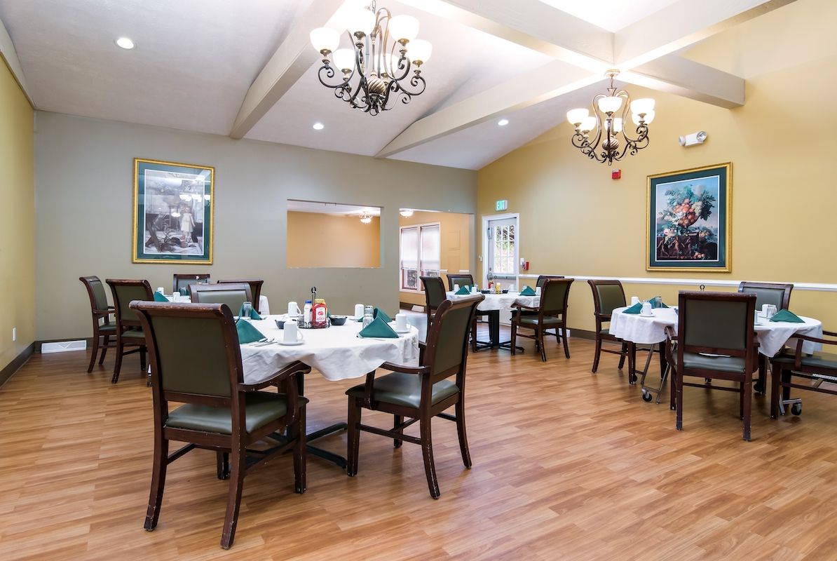 A well-lit dining area with elegant chandeliers and neatly arranged tables and chairs.