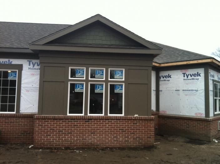 A house under construction with new windows and a partially completed brick exterior.