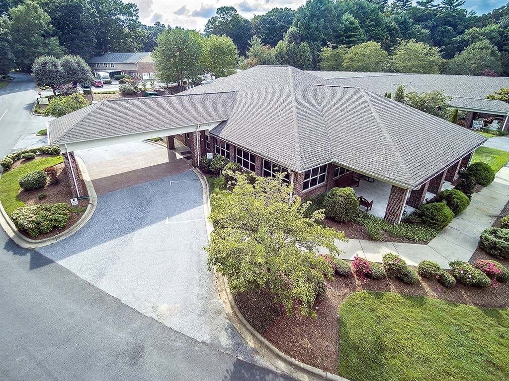 Aerial view of a building with surrounding greenery and a driveway.