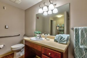 A well-lit bathroom with a vanity, mirror, and neatly arranged towels.
