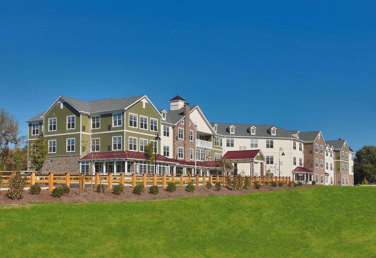 A picturesque view of a multi-story residential building with a grassy foreground and clear blue sky.