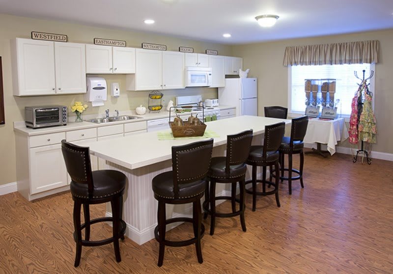 A spacious kitchen with a large island countertop surrounded by bar stools and equipped with modern appliances.